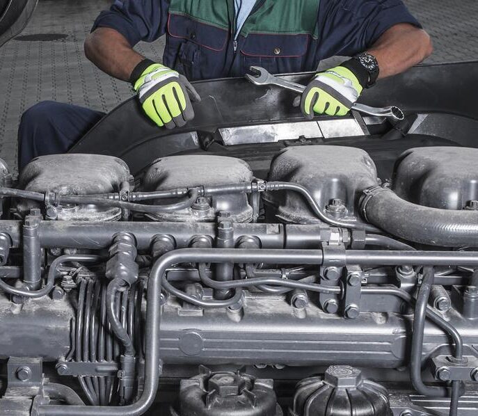 A mechanic with a large wrench working on a large diesel engine